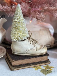 a pair of white shoes sitting on top of a book next to a pink christmas tree