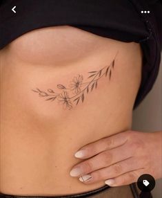 a woman's stomach with flowers and leaves tattooed on her side ribcage