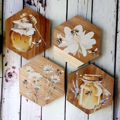 three honey jars with flowers painted on them are hanging from wooden hexagonals