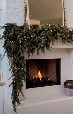 a fireplace decorated with christmas lights and greenery