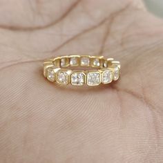 a close up of a person's hand holding a gold ring with diamonds on it