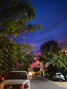 a white car parked on the side of a road next to tall buildings at night