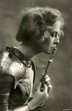 an old black and white photo of a woman holding a flower in her hand,