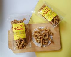 two bags of food sitting on top of a wooden cutting board next to a bag of chicken rings