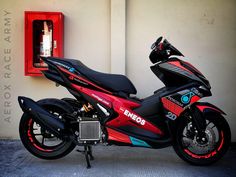 a red and black motorcycle parked in front of a wall mounted phone box with the word endos written on it