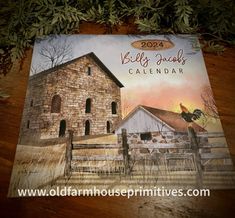 a calendar with an image of a barn and rooster on it sitting on a wooden table