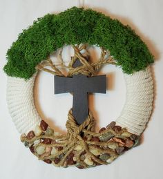 a wreath with a cross hanging from it's center surrounded by nuts and grass