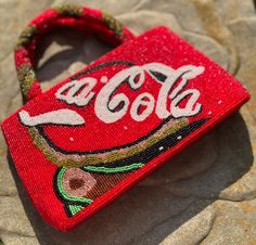 A super cute, sparkly mostly red beaded mini-handbag with lots of vintage charm! This intricately beaded Coca Cola bag is in excellent condition, with a clean red satin interior.  Just waiting to go out and party! Adorable! And, the nostalgia! This is a small top handle bag, beaded on both sides and the handles are beaded all the way around. This purse is 10" by 5.5" by 1 3/4" deep.  I was able to put a cell phone, 2 lipsticks, keys, iPods, card holder, powder compact in this bag with a bit of r Red Purse, Pretty Rocks, Powder Compact, Red Purses, Purse Vintage, Mini Handbag, Rock Candy, Christmas Truck, Beaded Purses