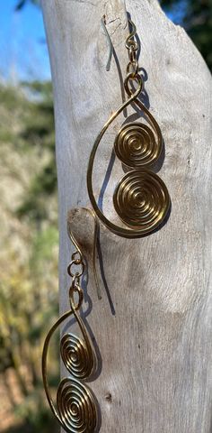 the earrings are hanging from the wooden post on the tree trunk, which has been made to look like spirals