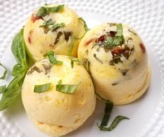 three small pastries on a white plate with green leaves