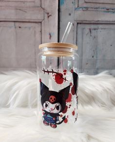 a glass jar with a cartoon cat painted on the side and a straw in it