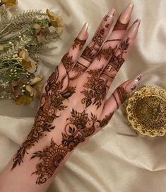 a woman's hand with henna on it next to a gold coin and flowers