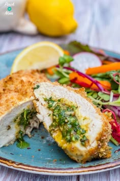 a blue plate topped with chicken cut in half next to a salad and lemon wedge