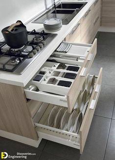 an open drawer in the middle of a kitchen with dishes and utensils on it