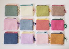 nine small zippered pouches lined up on a white surface, each with different colored handles