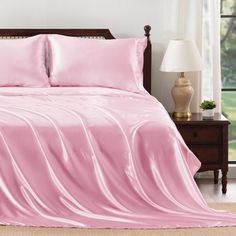 a bed covered in pink sheets and pillows