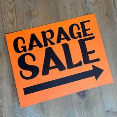 an orange garage sale sign sitting on top of a wooden floor