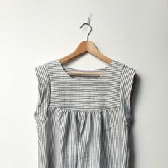 a white and black striped top hanging on a wooden hanger