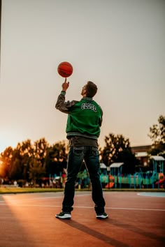 a man in green shirt playing with a red ball on basketball court at sunset or dawn