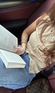 a woman sitting in a car reading a book