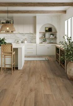 an open kitchen with white cabinets and wood flooring is pictured in this image, there are plants on the counter