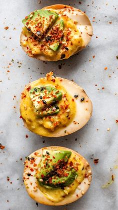 three pieces of bread with toppings on them sitting on top of a white surface