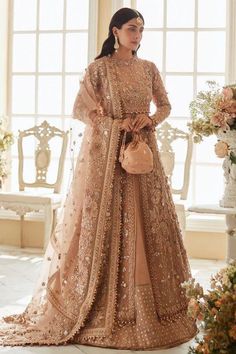 a woman standing in front of a window wearing a brown lehenga