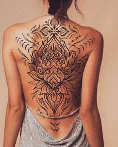 the back of a woman's body with an intricate tattoo design on her chest