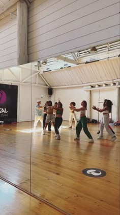 a group of people standing on top of a wooden floor in front of a mirror