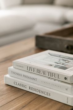 three books sitting on top of a wooden table next to a white couch in a living room