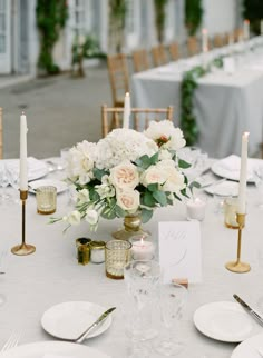 the table is set with white flowers and candles for an elegant wedding reception or special event