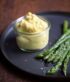 asparagus and mayonnaise on a black plate