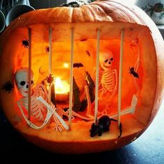 a carved pumpkin with skeletons and candles in it