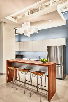 a modern kitchen with stainless steel appliances and wooden counter tops, along with two stools