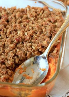 a close up of a spoon in a casserole dish with crumbled toppings