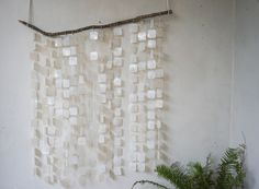 a wall hanging made out of ice cubes on a white wall next to a potted plant