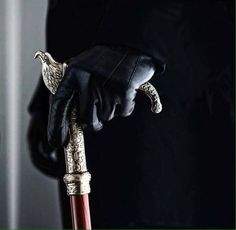 a person wearing black gloves and holding an ornate handle