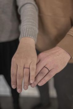 two people holding each other's hands with their fingers touching one another while the other holds