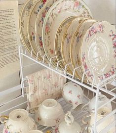 a rack filled with lots of plates and dishes on top of a white tablecloth