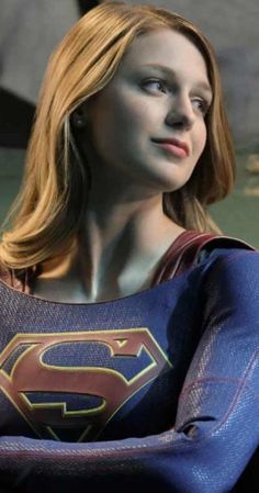 a close up of a person wearing a superman costume with her arms crossed and looking off to the side