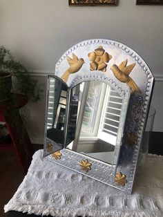 a mirror with birds on it sitting on top of a table