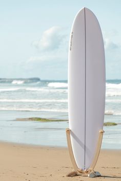 a white surfboard sitting on top of a sandy beach