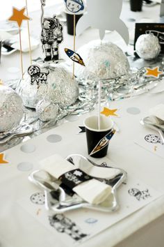 a table topped with lots of silver and white desserts covered in confetti