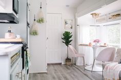 a kitchen and dining area with white walls, wood floors and pink chairs in front of the table