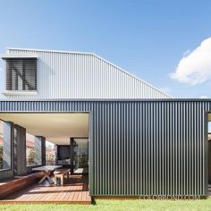 an outdoor area with wooden decking and metal cladding on the side of a house