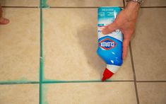 someone is cleaning the floor with a blue and red spray bottle on top of it