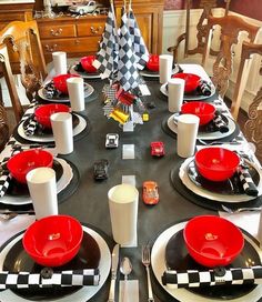 the table is set with black and white checkered plates, silverware, and red dishes