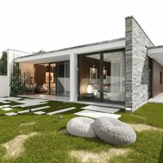 a modern house with grass and stones on the ground, in front of it is a patio