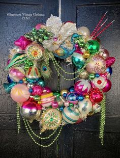 a wreath with ornaments hanging on the front door, decorated with beads and feathers for christmas