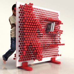 a man standing next to a red and white sculpture with circles on it's side